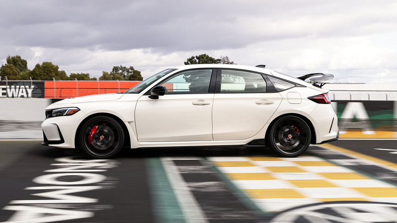 Side view of white Honda Civic Type R driving on race track.