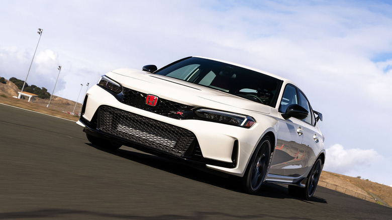 Front view of white Honda Civic Type R driving on race track.