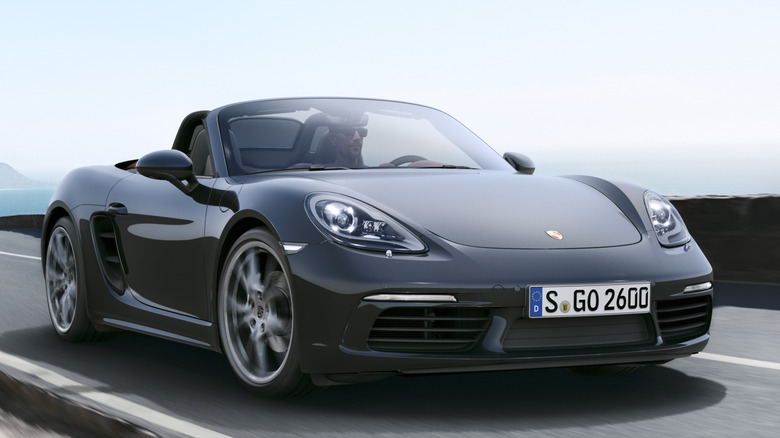 Front 3/4 view of Porsche Boxster on winding road in seaside setting