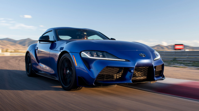 Toyota GR Supra cornering on track, front 3/4 view, blue exterior