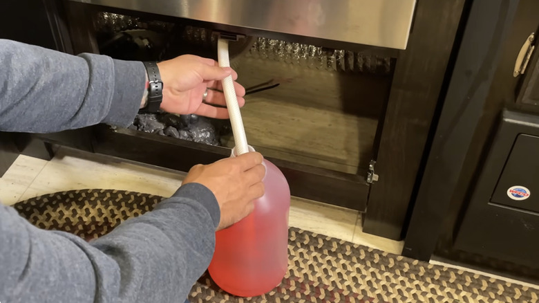 Person inserting RV hose into a jug of antifreeze