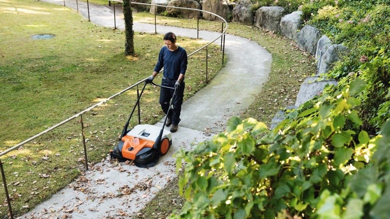 Person using a Stihl sweeping machine to clear a pathway