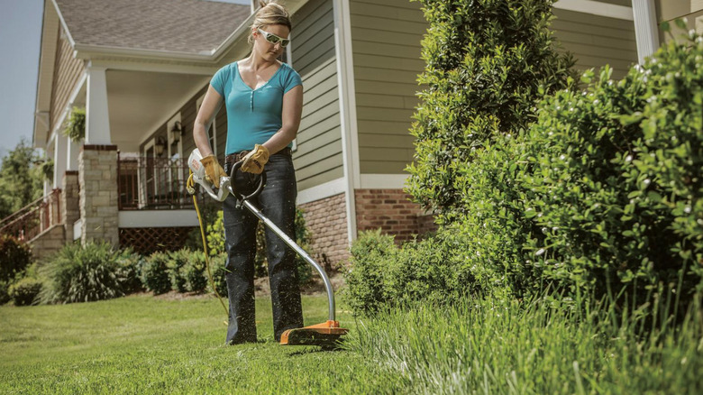 A person using the Stihl FSE 60 120-Volt Electric-Powered Grass Trimmer in a yard near a house.