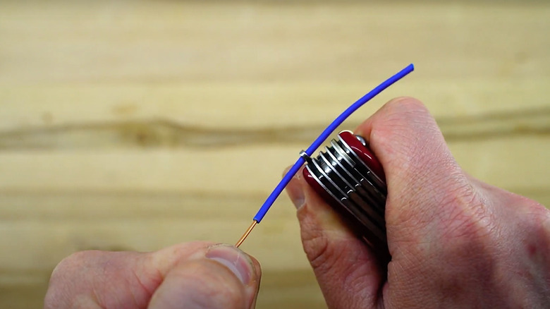 man stripping wire with keyring eyelet