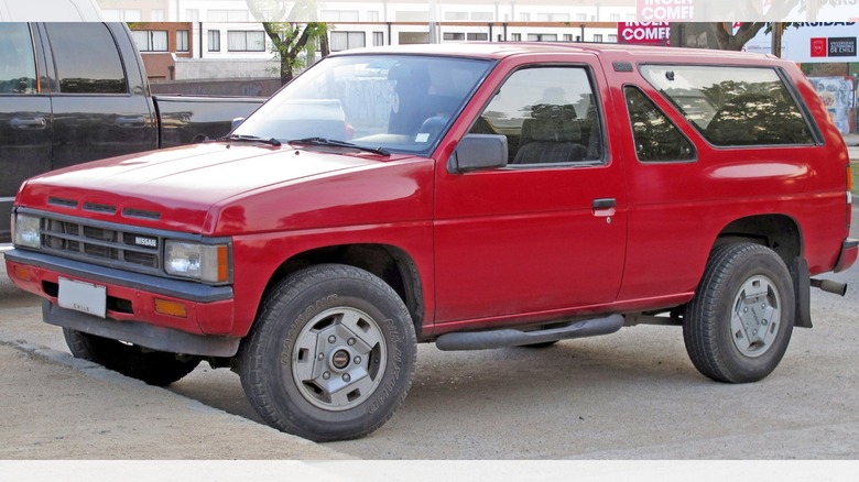 a red 1989 Nissan Pathfinder in a parking lot