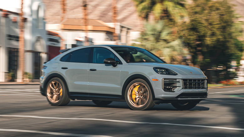 A gray Porsche Cayenne Turbo GT being driven down a road with a blurred background.