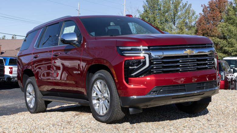 A red Chevrolet Tahoe parked on gravel.