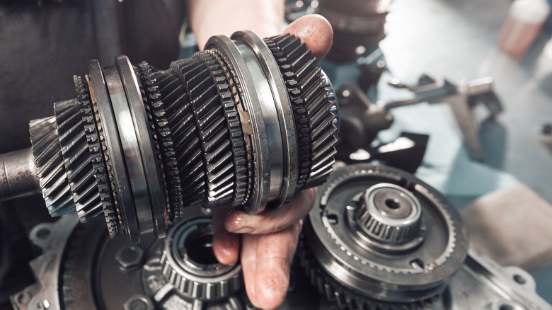A close-up of a transmission cross-section held in a mechanic's hand.