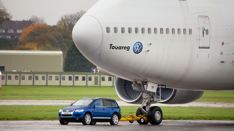 A Volkswagen Touareg V10 TDI SUV towing a Boeing 747 Jumbo Jet on an airport tarmac