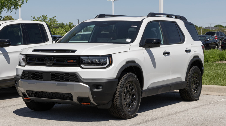 Front 3/4 of white Honda Passport SUV parked on dealership lot.