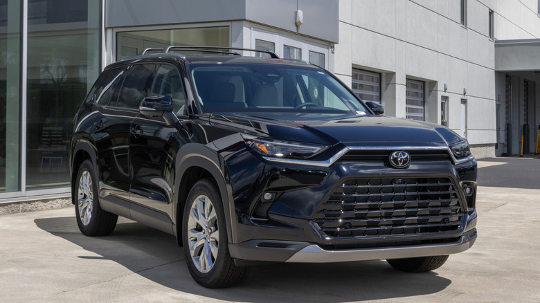 Front 3/4 view of black Toyota Grand Highlander parked in front of Toyota dealership.