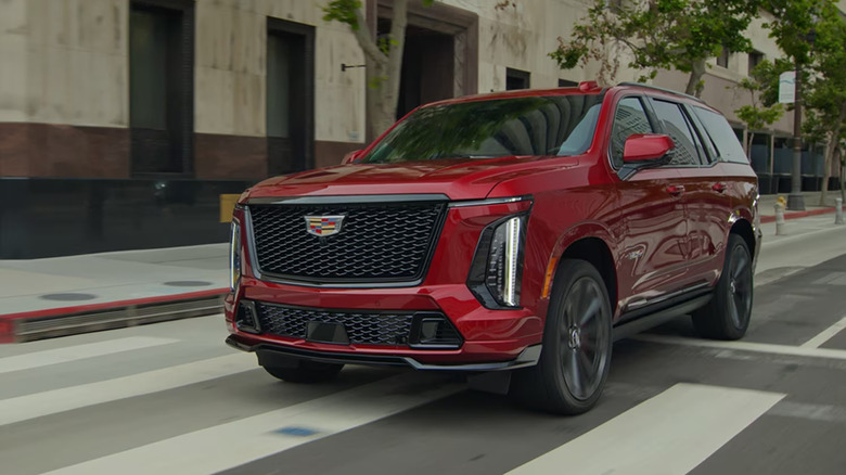 A red Cadillac Escalade-V driving down a city street.
