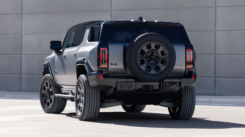 A silver GMC Hummer EV SUV sitting by a white building.