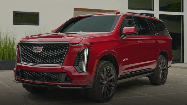 A red Cadillac Escalade-V parked near a fancy building.