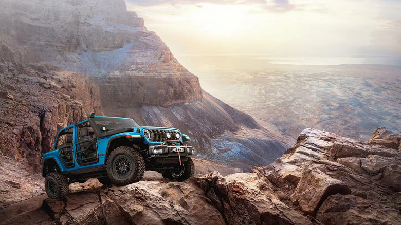 A blue Jeep Wrangler with the doors taken off climbing a mountain.