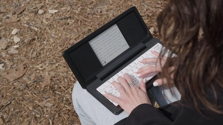 A woman typing on a Zerowriter Fold in an outdoor setting