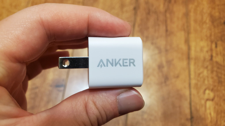 Person holding a plug with Anker brand name printed on the side