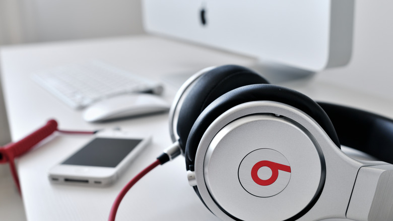 A Beats Audio headphones kept on a table next to an iPhone and an iMac