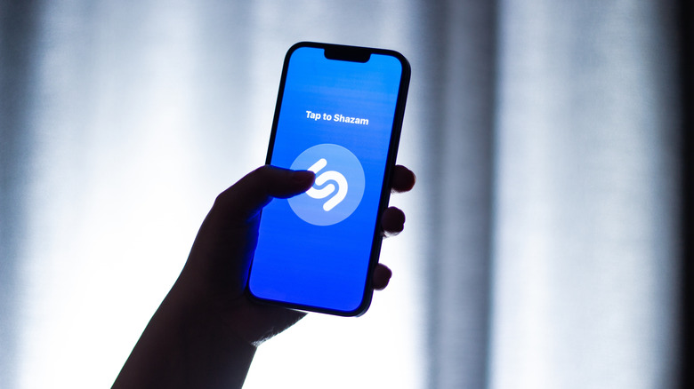 A person holding a phone running the Shazam app