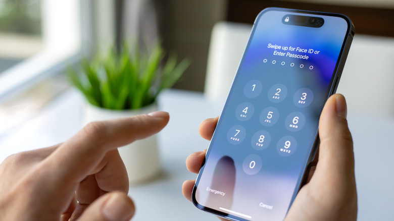 Person holding iPhone 15 with lock screen showing