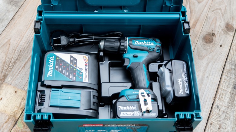 Makita electric drill in box with charger and battery.