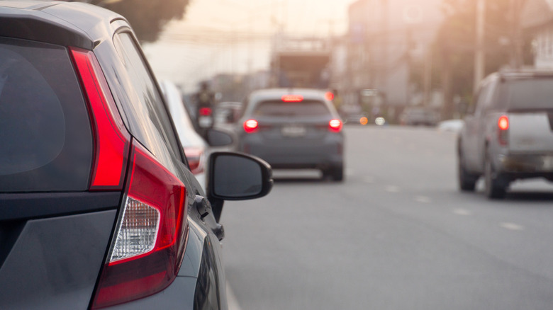 Cars moving normally on an asphalt road with their rear brake lights on, indicating they're slowing down by applying the brakes.