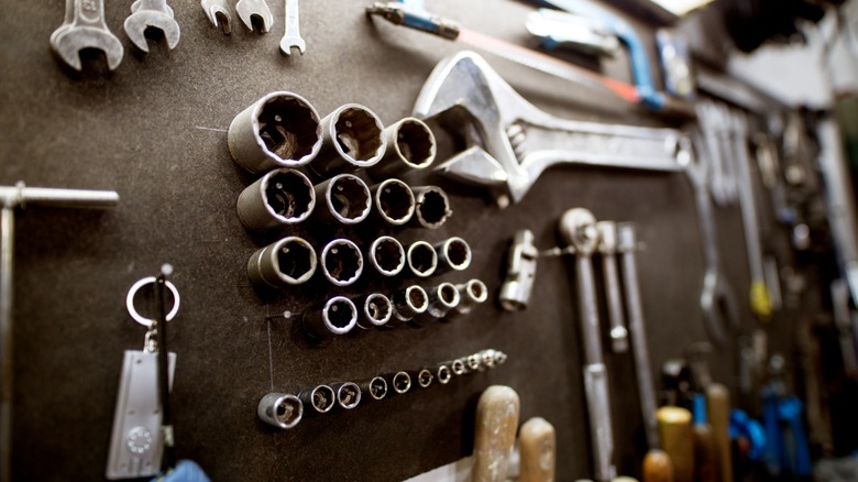 A selection of hand tools hanging on a workbench pegboard wall.