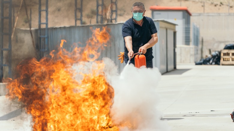 Using a fire extinguisher during training on its use.