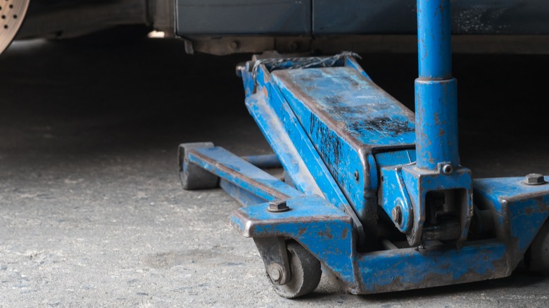 Using a floor jack to lift a car from a garage floor.