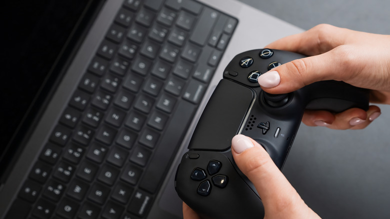 A person using a wireless controller with a MacBook