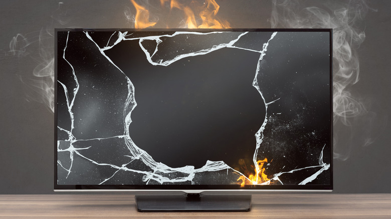 A burning and smoking TV with a cracked screen