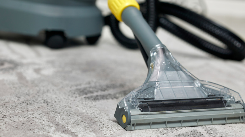 Close-up of a gray and yellow carpet cleaner on a gray patterned carpet