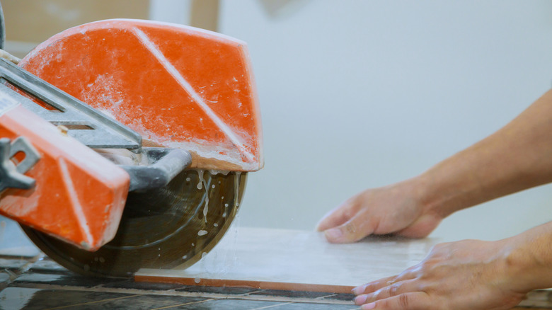 A worker using a wet saw to cut a tile