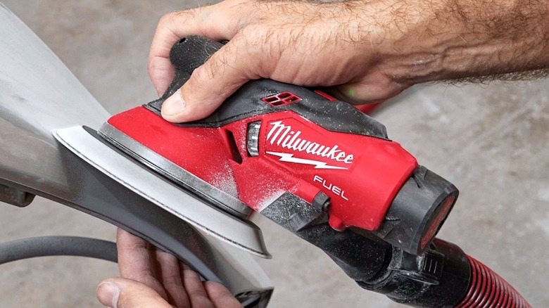 Person using Milwaukee Tools orbital sander