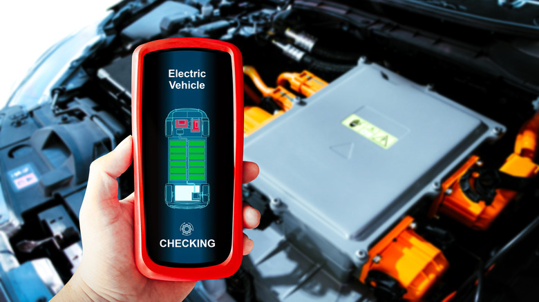 A device being used to service an electric vehicle, motor in the background.
