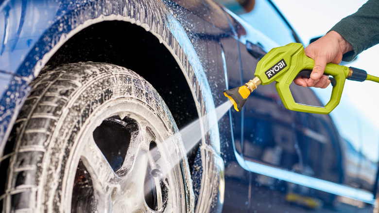 A Ryobi 1200 PSI 1.8 GPM pressure washer used to clean a car wheel.