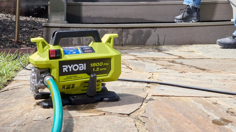 The Ryobi 1,800 PSI 1.2 GPM Electric Pressure Washer, near some stairs, outside.