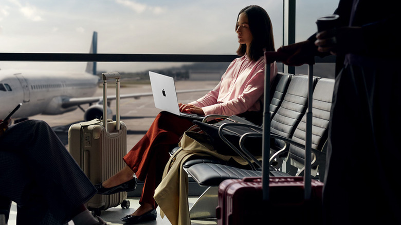 A woman using a MacBook at an airport