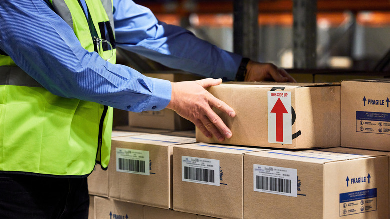 Worker in third-party seller warehouse piling up boxes for shipping