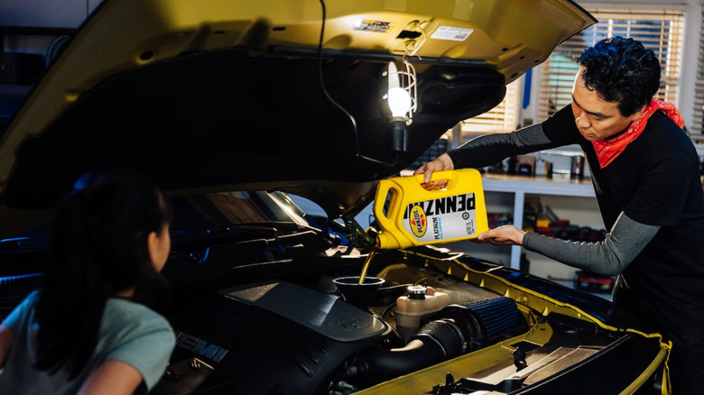 man pouring engine oil into the engine