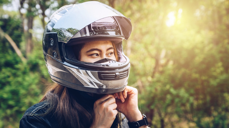 Person putting on motorcycle helmet before riding motorcycle