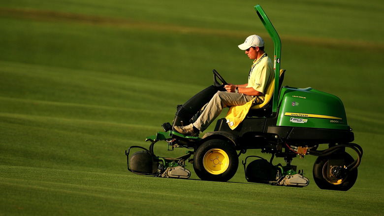 Side view of a person operating a riding mower.