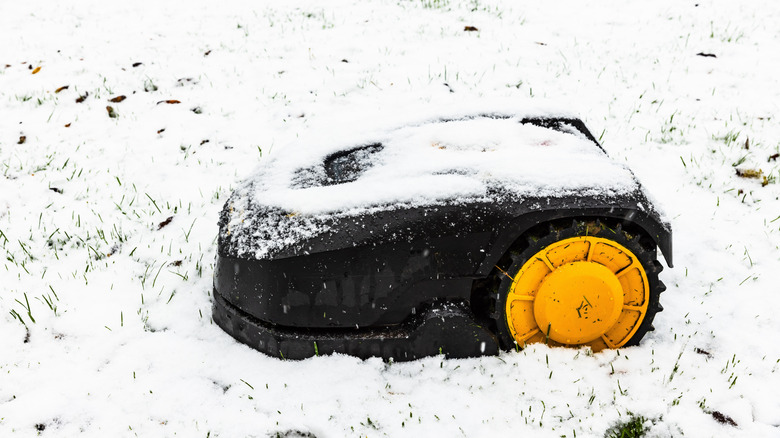 A robot lawn mover with snow on top of it.