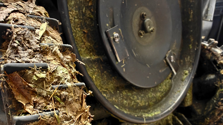 A robot lawn mower with mud and debris stuck in the wheel.