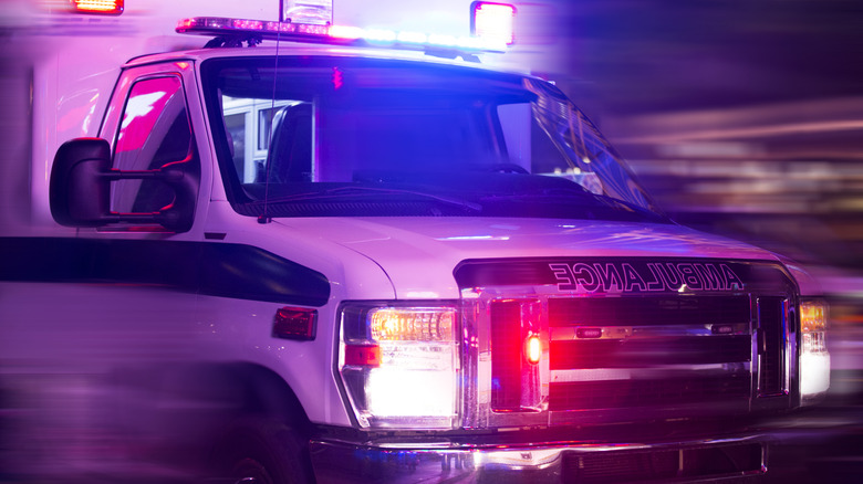 A white ambulance on the road at night with the lights lit