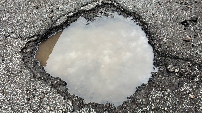 Close up of a pothole full of water in the road.