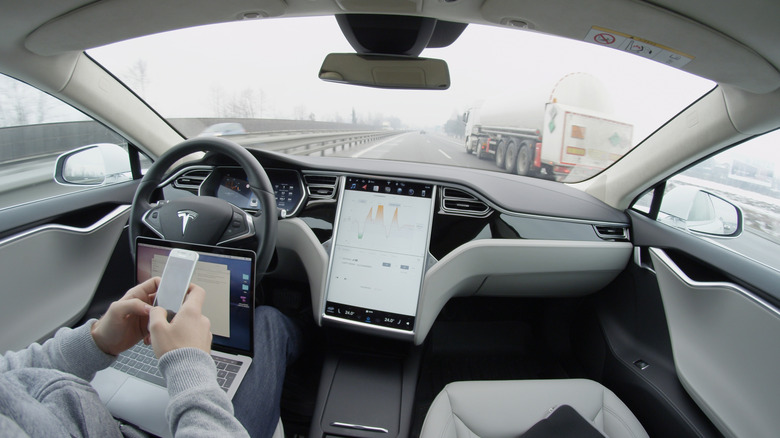 Tesla self-driving while driver uses phone and laptop
