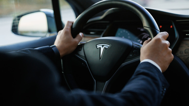 man in suit driving a Tesla