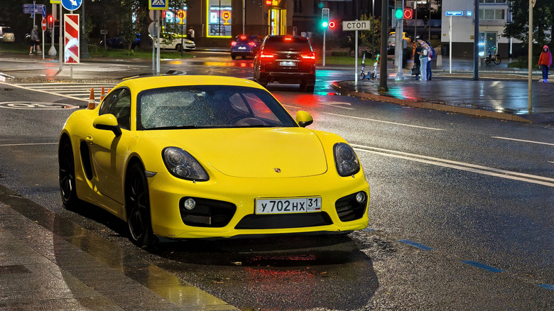 A yellow Porsche parked on a street on a rainy night