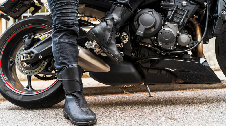 Motorcycle boots on the legs of a female rider sitting on a motorcycle